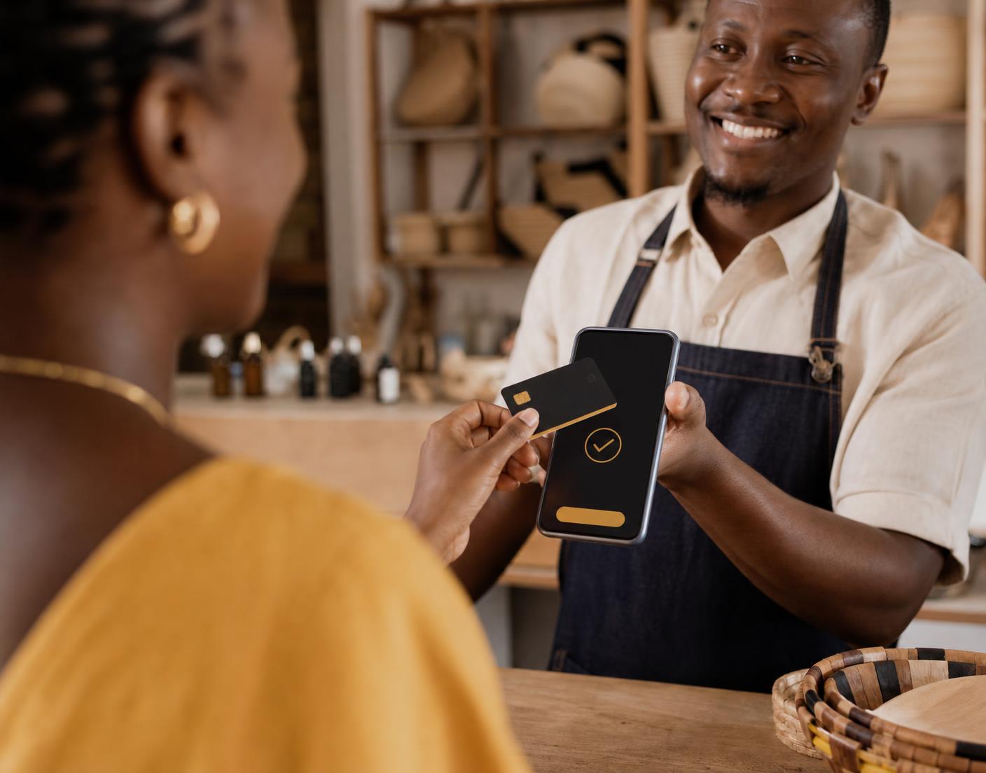 A shop owner in Botswana accepting a contactless card payment on a phone